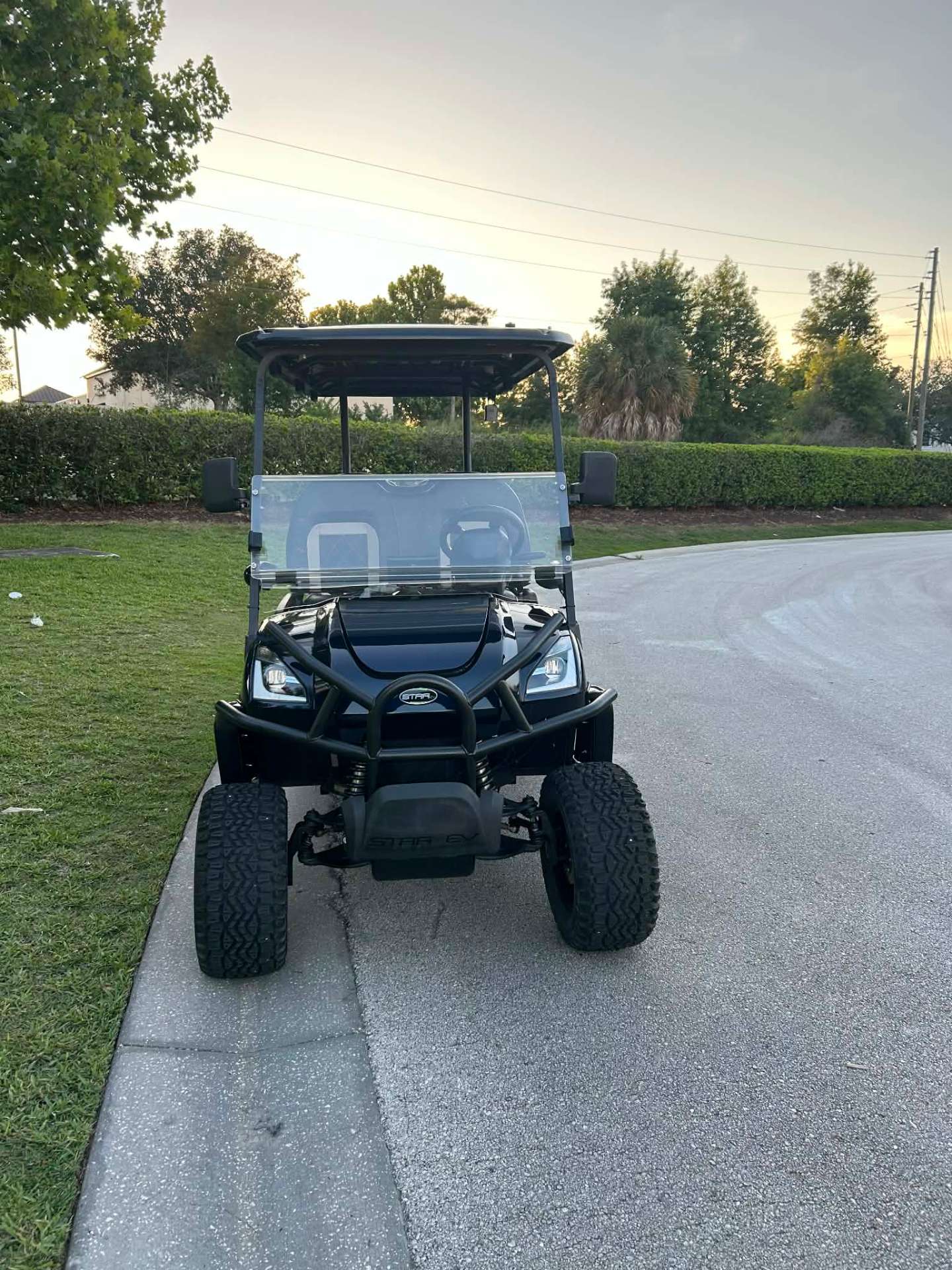 Front view of black Star EV luxury golf cart at sunset on a Central Florida street