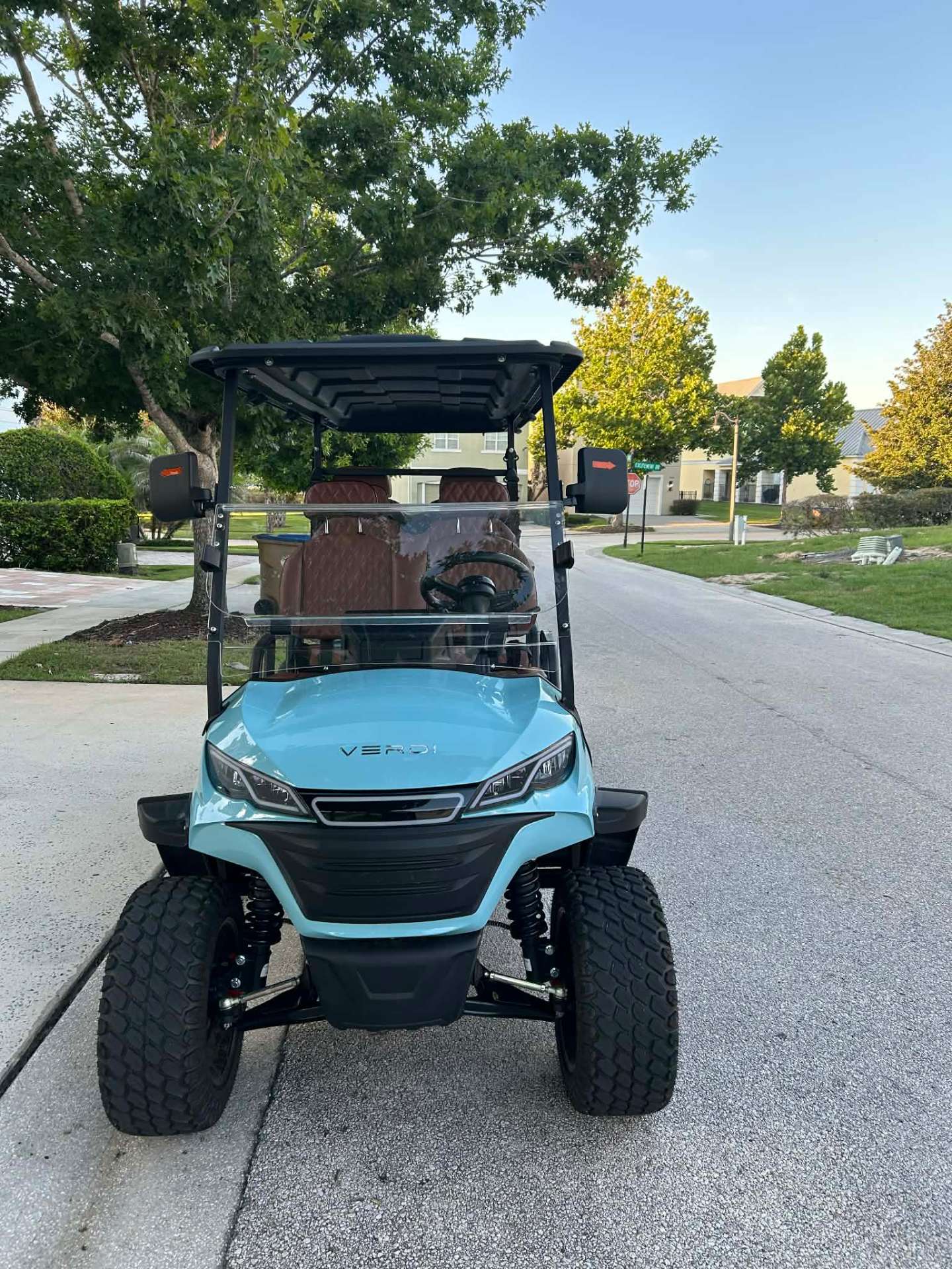 Front view of teal Verdi luxury golf cart on a Central Florida resort street